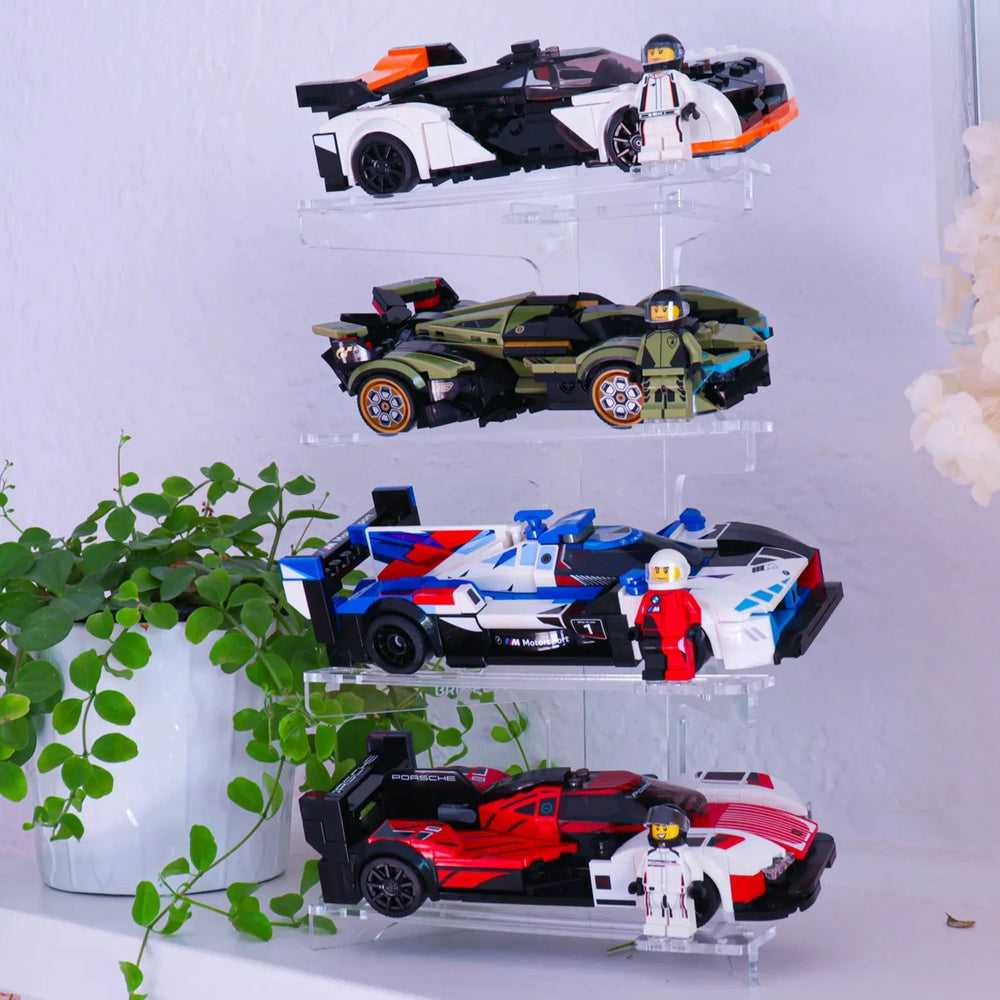 
                  
                    Clear acrylic display tower with toy cars on a white surface with decorative elements.
                  
                
