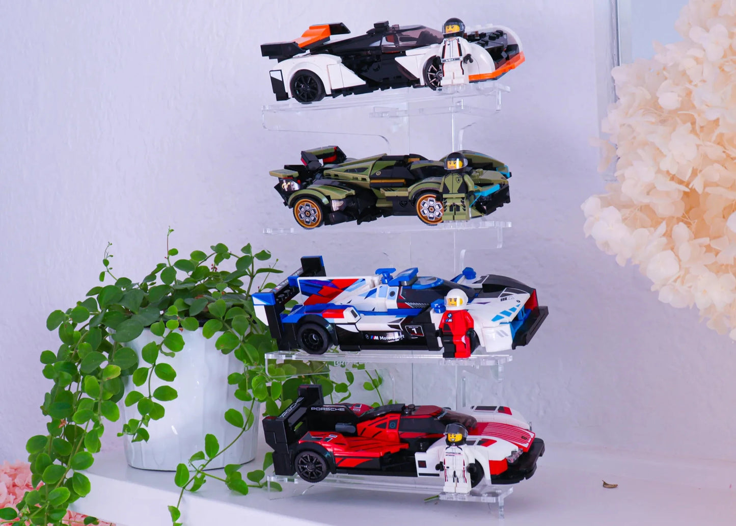 Clear acrylic display tower with toy cars on a white surface with decorative elements.